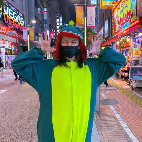 Ein Mädchen trägt glücklich einen Dinosaurier-Kigurumi in einer überfüllten Straße