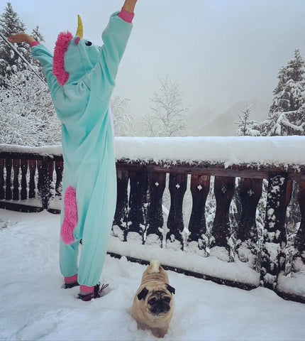 Ein Mädchen trägt glücklich einen blauen Einhorn-Kigurumi im Schnee